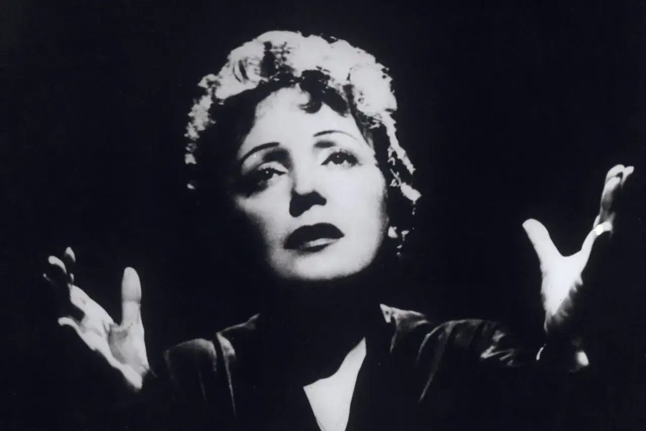Edith Piaf, jedna z najsłynniejszych francuskich piosenkarzy, w dramatycznym geście na scenie.