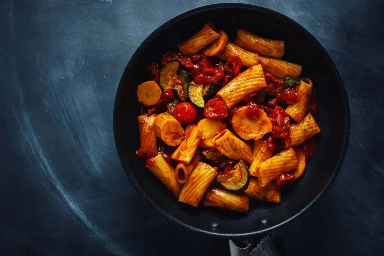 Rigatoni con verduras y salsa de tomate en sartén, ideal para una tabla de dieta para engordar.