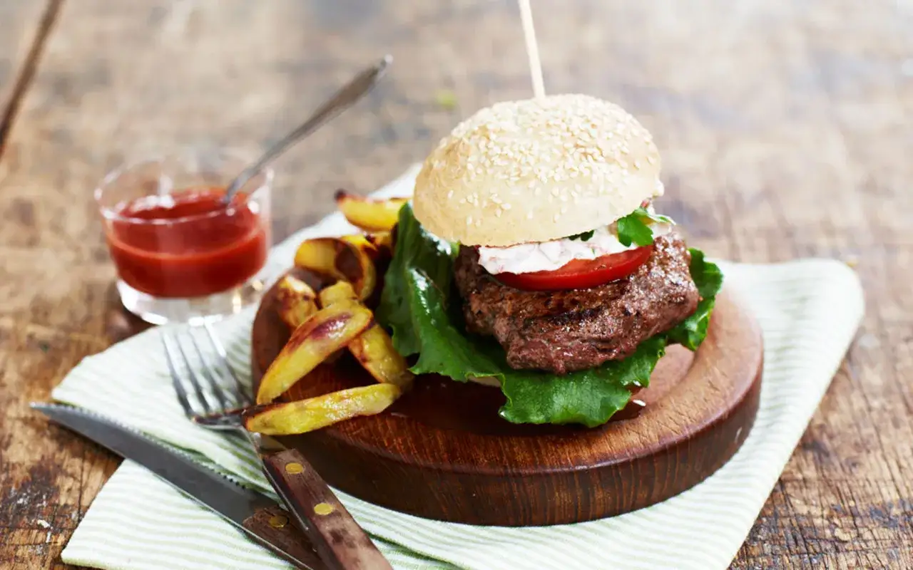 En saftig hamburgare med pommes frites och ketchup. Ett perfekt hamburgare recept för en härlig måltid.