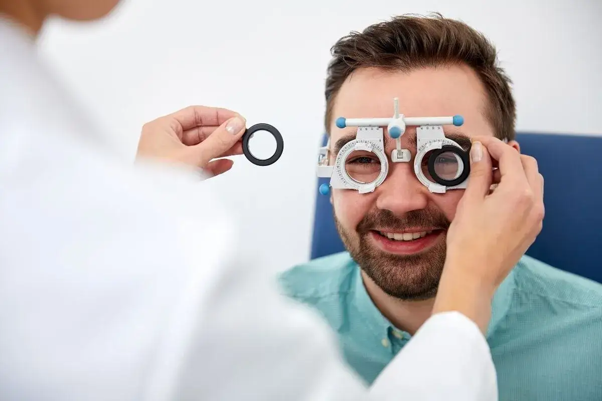 Badanie wzroku u optometrysty. Czy noszenie okularów pogarsza wzrok? Pacjent uśmiecha się, gdy specjalista testuje soczewki.