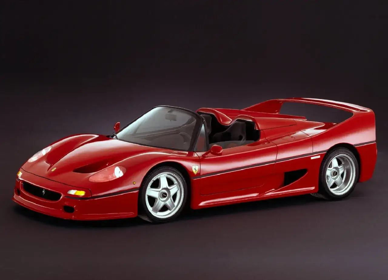 Roter F50 Ferrari Roadster, ein Traumauto mit offenem Verdeck, steht vor dunklem Hintergrund.