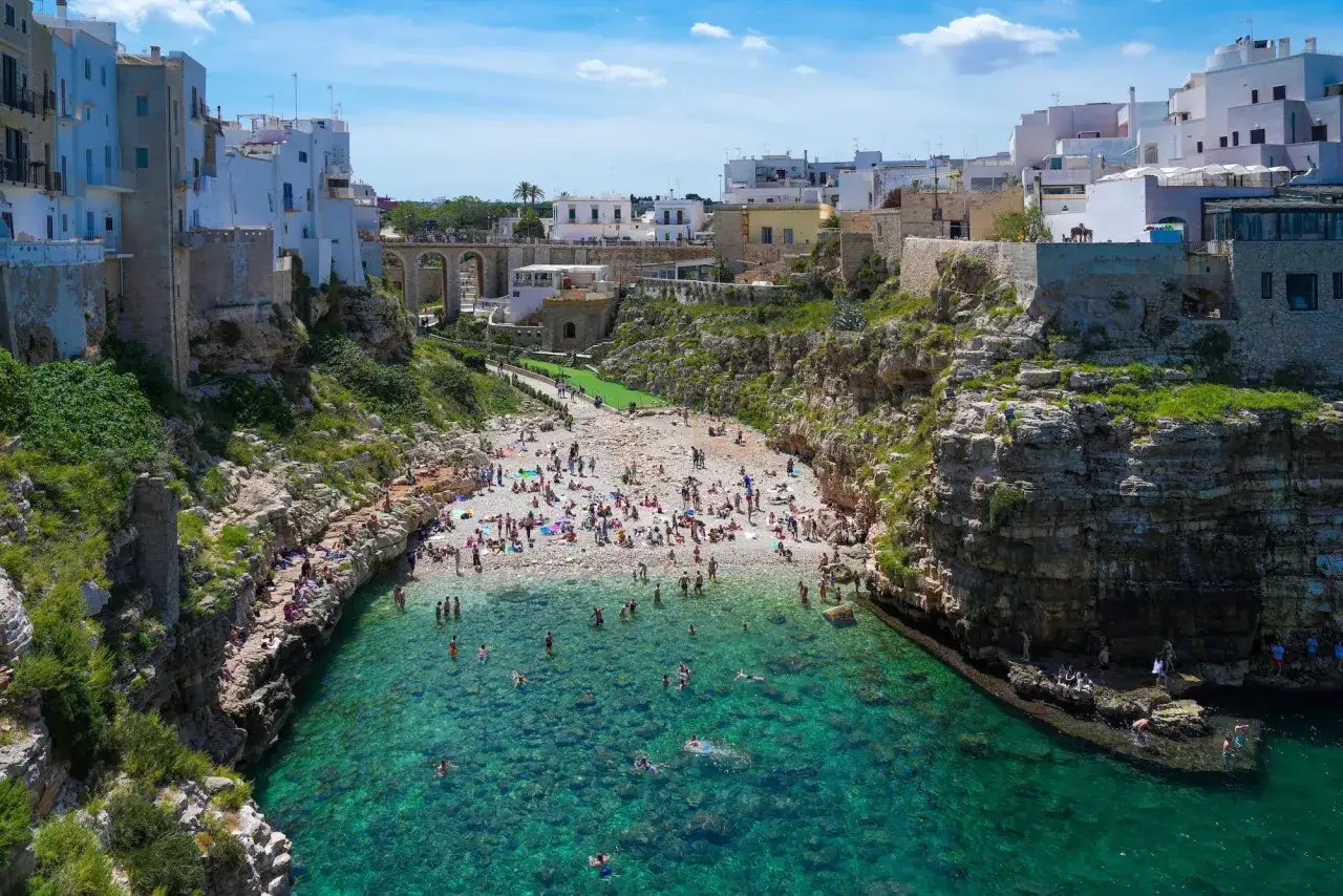 Spiaggia affollata e mare cristallino a Polignano a Mare. Perfetto per scoprire cosa fare in questa perla pugliese: nuotare, prendere il sole e godersi il panorama.