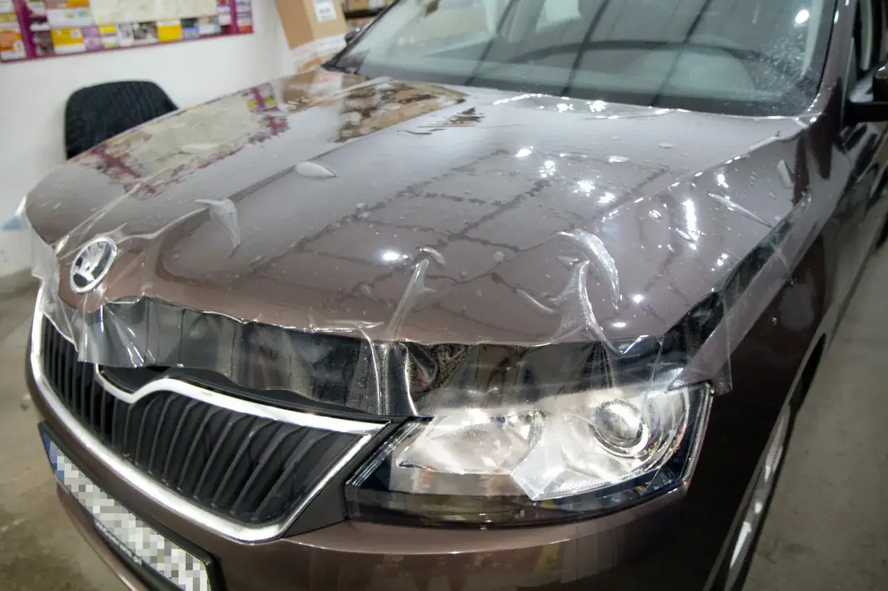 Brązowa Skoda z folią ochronną na masce. To jest właśnie folia PPF, kt&oacute;ra chroni lakier przed zarysowaniami.
