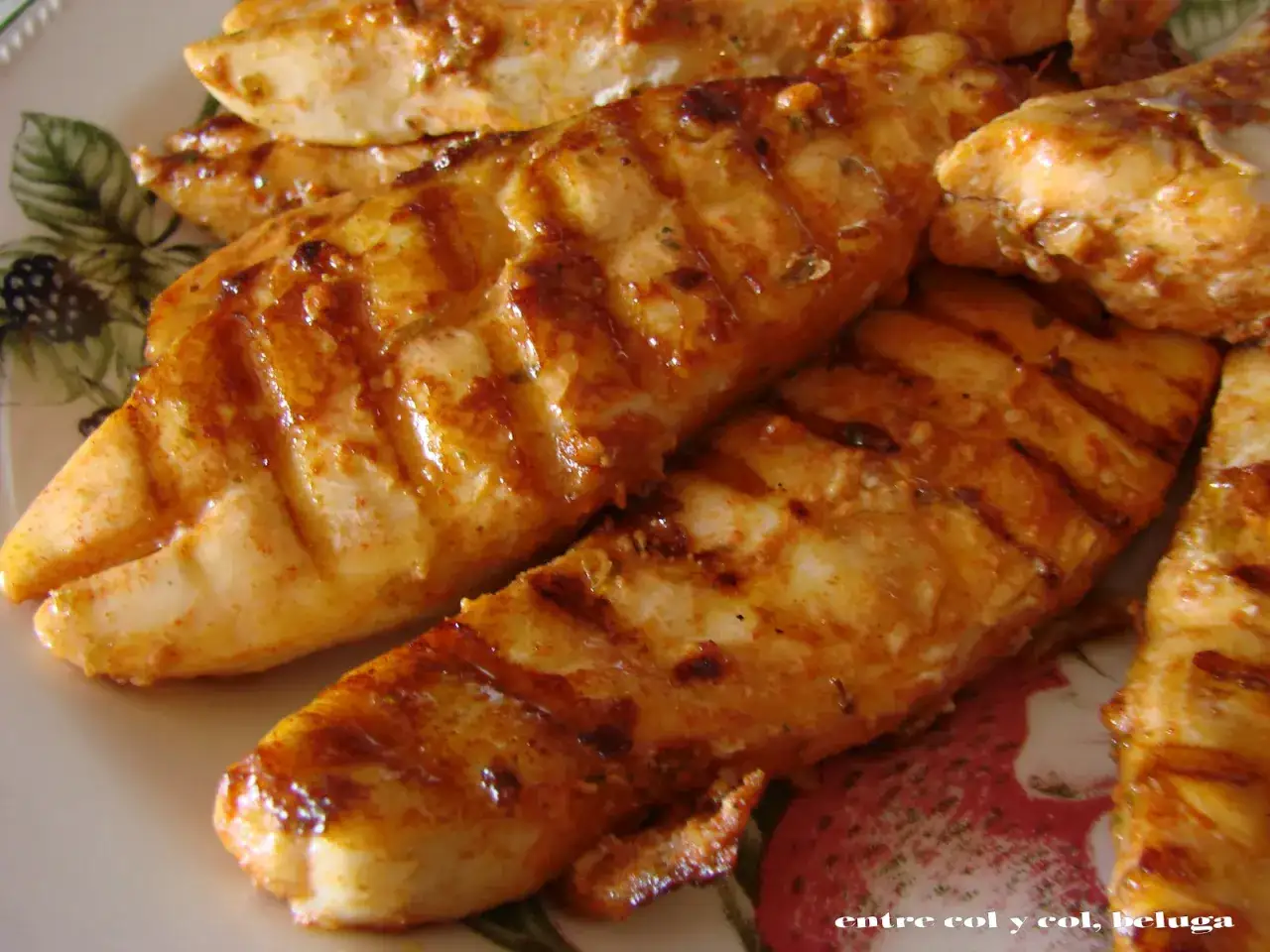 Filetes de japuta en adobo, dorados y con marcas de parrilla, servidos en un plato decorado con bayas.