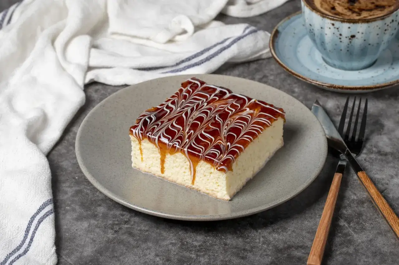 Pyszne ciasto tres leches z polewą karmelową i białą czekoladą, gotowe do zjedzenia z kawą.