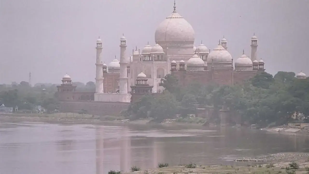 El Taj Mahal, un mausoleo de mármol blanco, se alza majestuoso junto a un río, donde está el Taj Mahal.