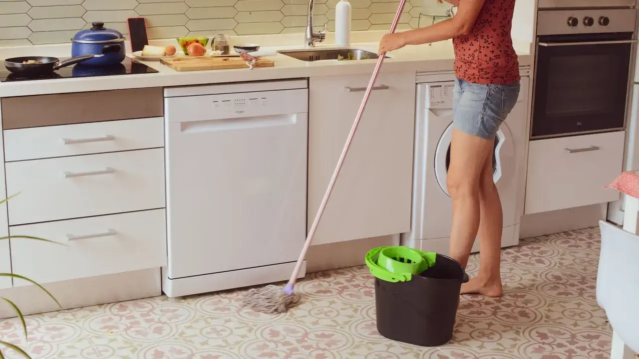 Persona friega el suelo de la cocina con una fregona y un cubo. Preg&uacute;ntate: &iquest;cada cuanto hay que fregar el suelo?