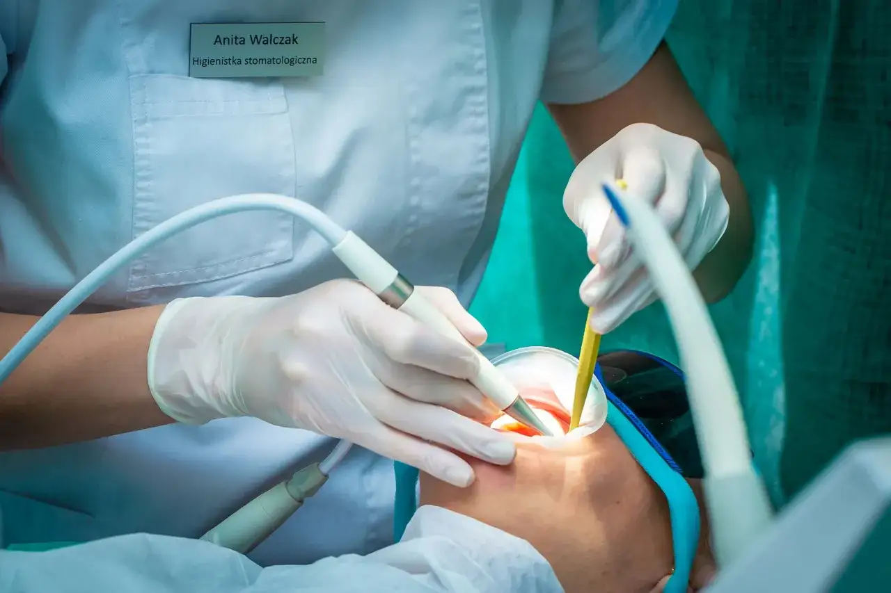 Higienistka stomatologiczna Anita Walczak wykonuje zabieg piaskowania zębów. Po zabiegu mogą wystąpić przejściowe efekty uboczne, jak nadwrażliwość.