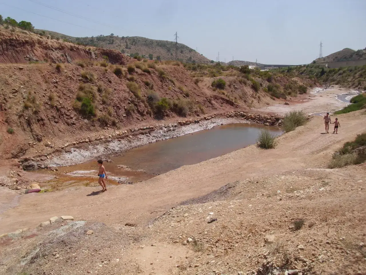 Ni&ntilde;os disfrutan de un d&iacute;a soleado en les salinetes de Novelda, un paisaje &aacute;rido con un peque&ntilde;o estanque.