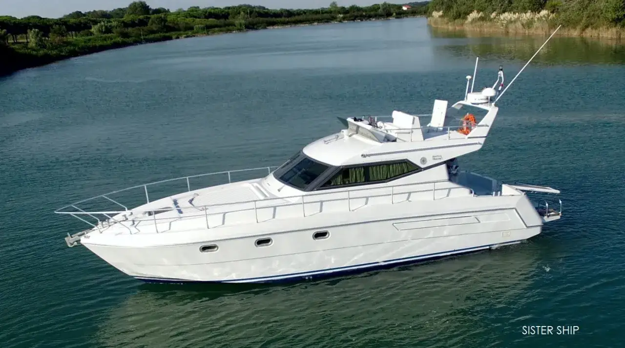 Yacht bianco Raffaelli Typhoon naviga su acque calme, circondato da vegetazione lussureggiante.