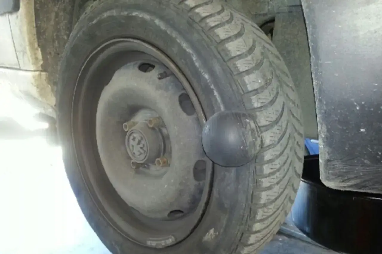 Gros plan sur une roue de voiture avec une hernie visible sur le pneu, signe d'un problème à réparer.