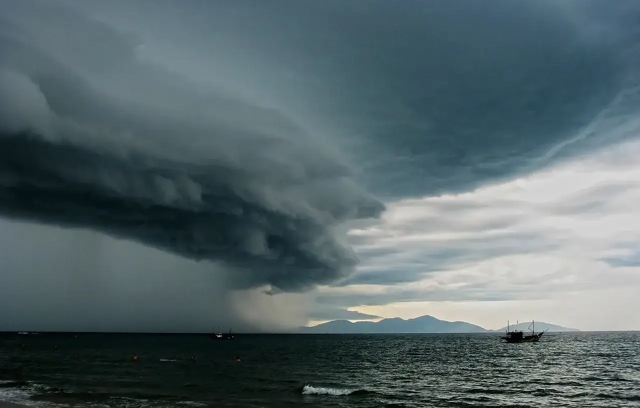Dramatisches Wetter in Thailand im August: Eine massive Gewitterwolke zieht &uuml;ber das Meer, Boote sind in der Ferne zu sehen.