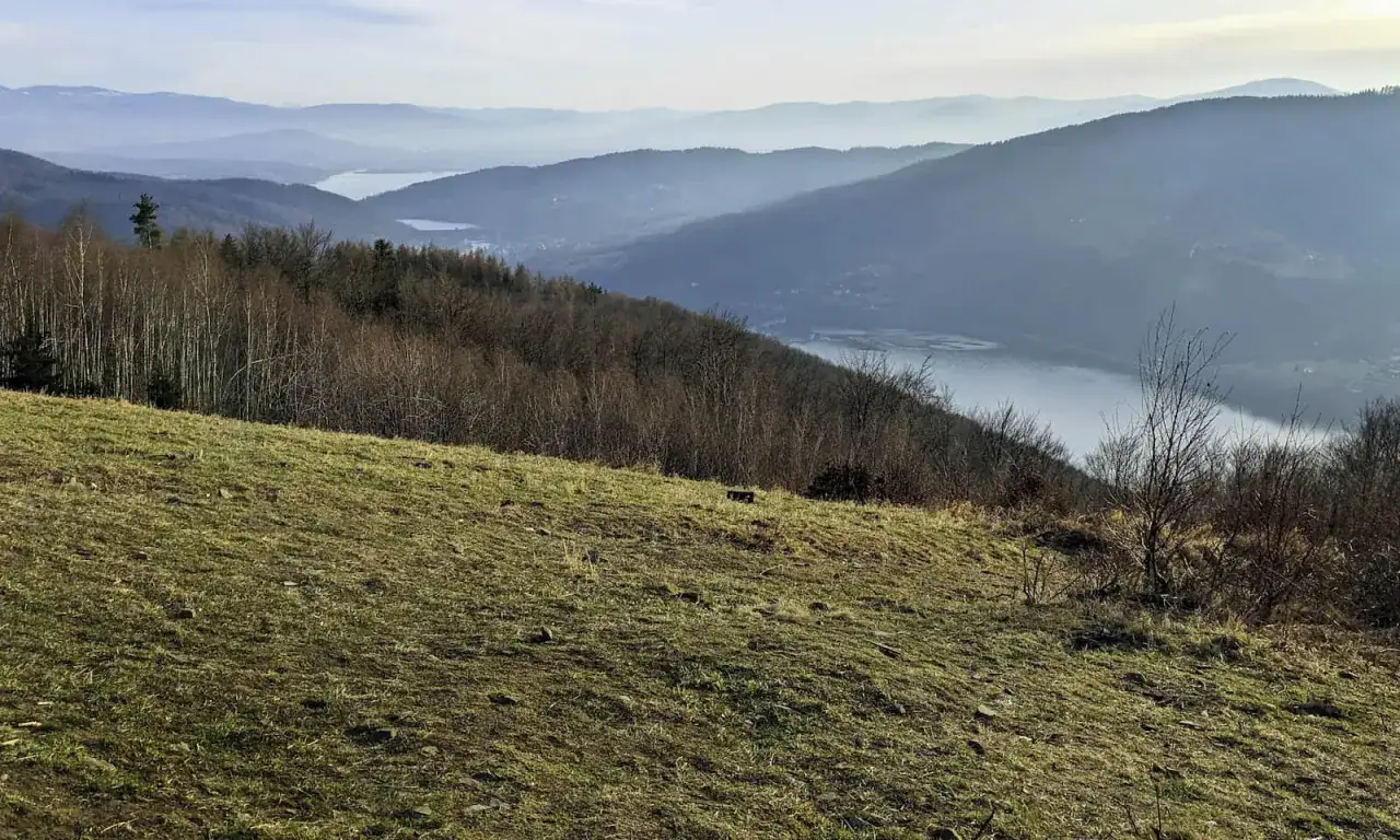 Widok na jezioro i góry w Beskidzie Małym. W oddali widać kolejne pasma górskie. Idealne miejsce na wędrówki po beskidzkich szlakach.