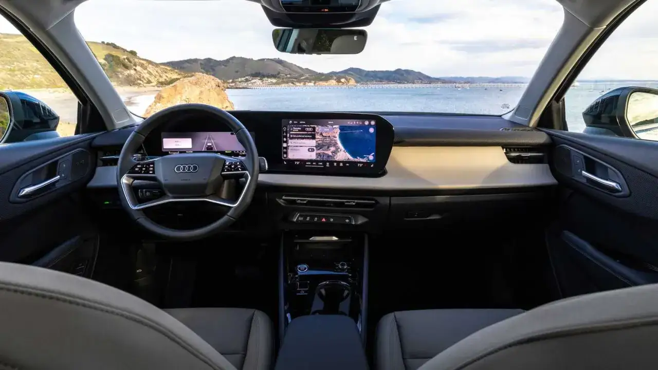 Wnętrze q3 audi z widokiem na ocean i wybrzeże. Kierownica, ekran nawigacji i deska rozdzielcza.