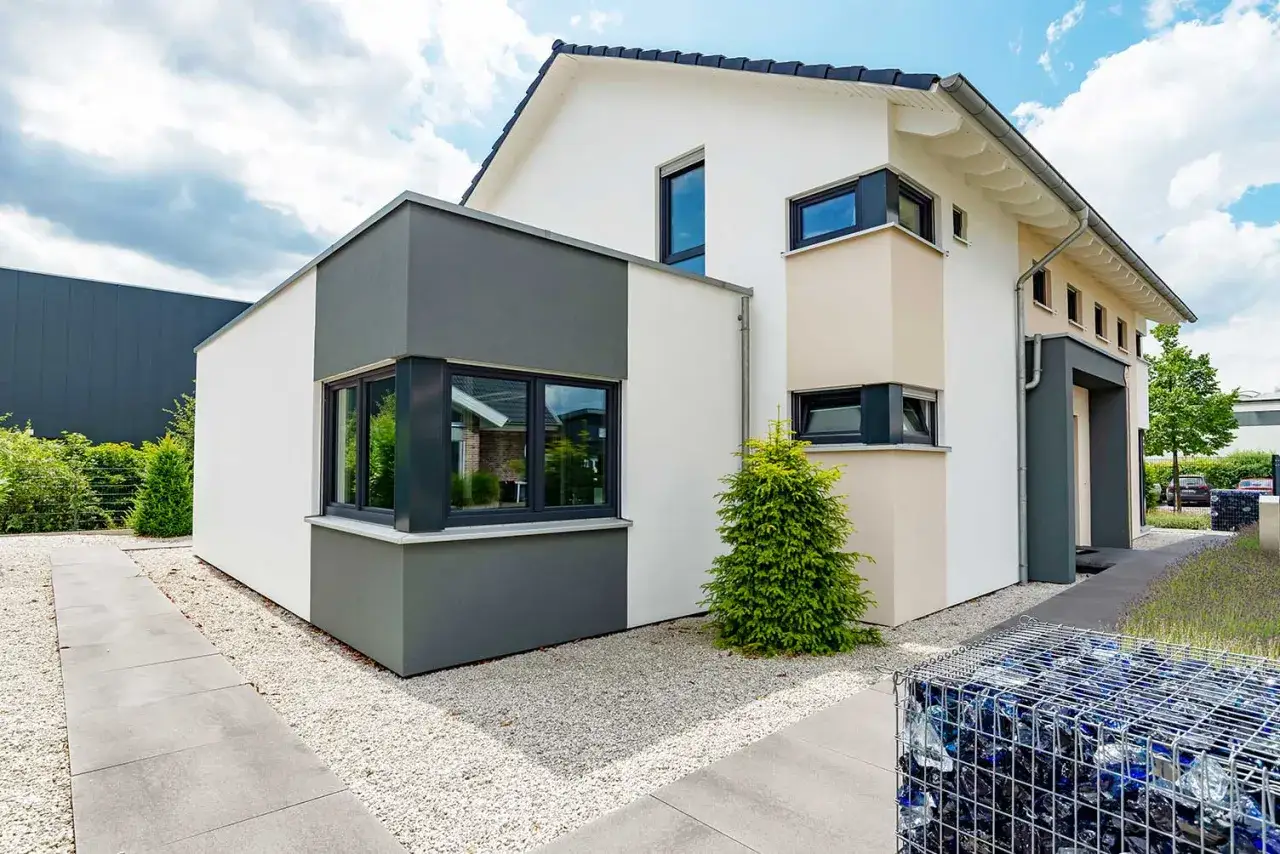 Modernes Haus mit anthrazitfarbenen Kunststofffenstern, die einen stilvollen Kontrast zur weißen Fassade bilden.