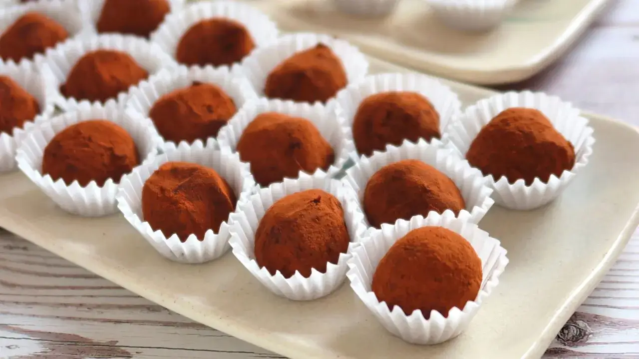 Deliciosas trufas de chocolate cubiertas de cacao, presentadas en sus envoltorios blancos.