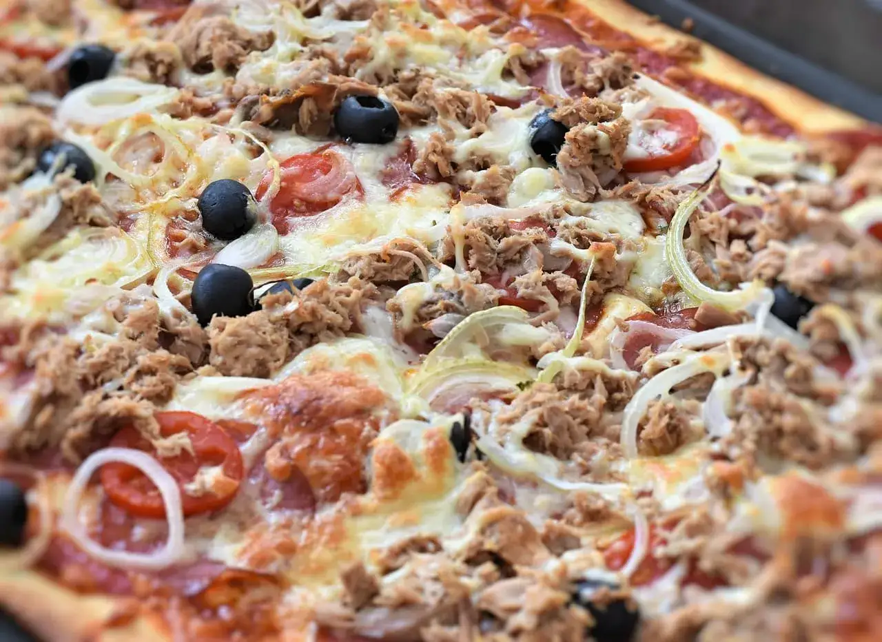 Pyszna pizza z tuńczykiem, oliwkami i cebulą, z roztopionym serem.