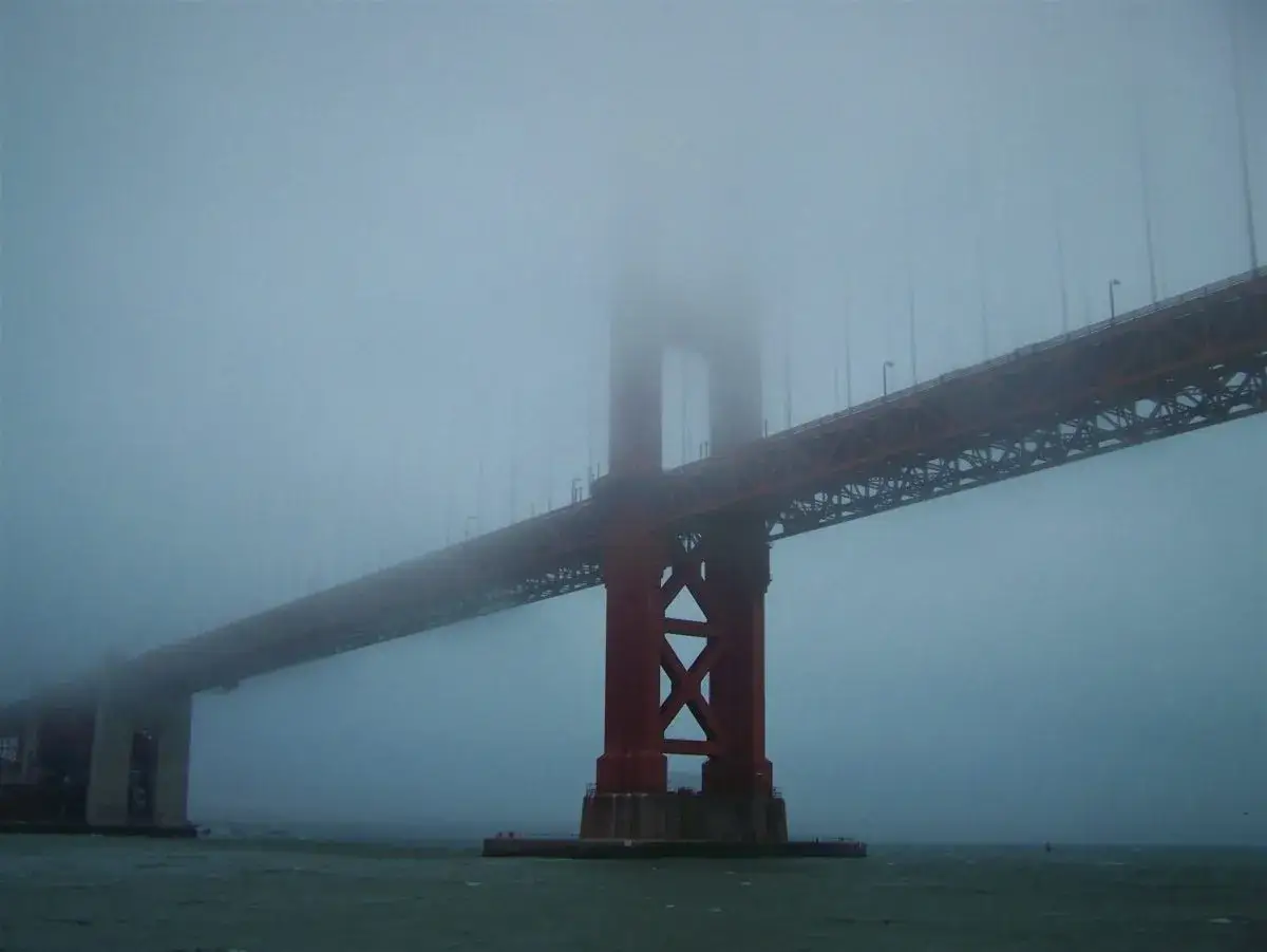 Mglisty, majestatyczny **most w San Francisco** wyłania się z gęstej mgły, tworząc tajemniczy widok.