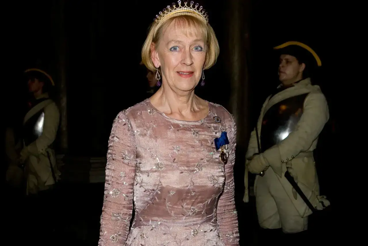 Åldfrun Ebba von Mecklenburg bär tiara och en broderad klänning, flankerad av vakter i historiska uniformer.
