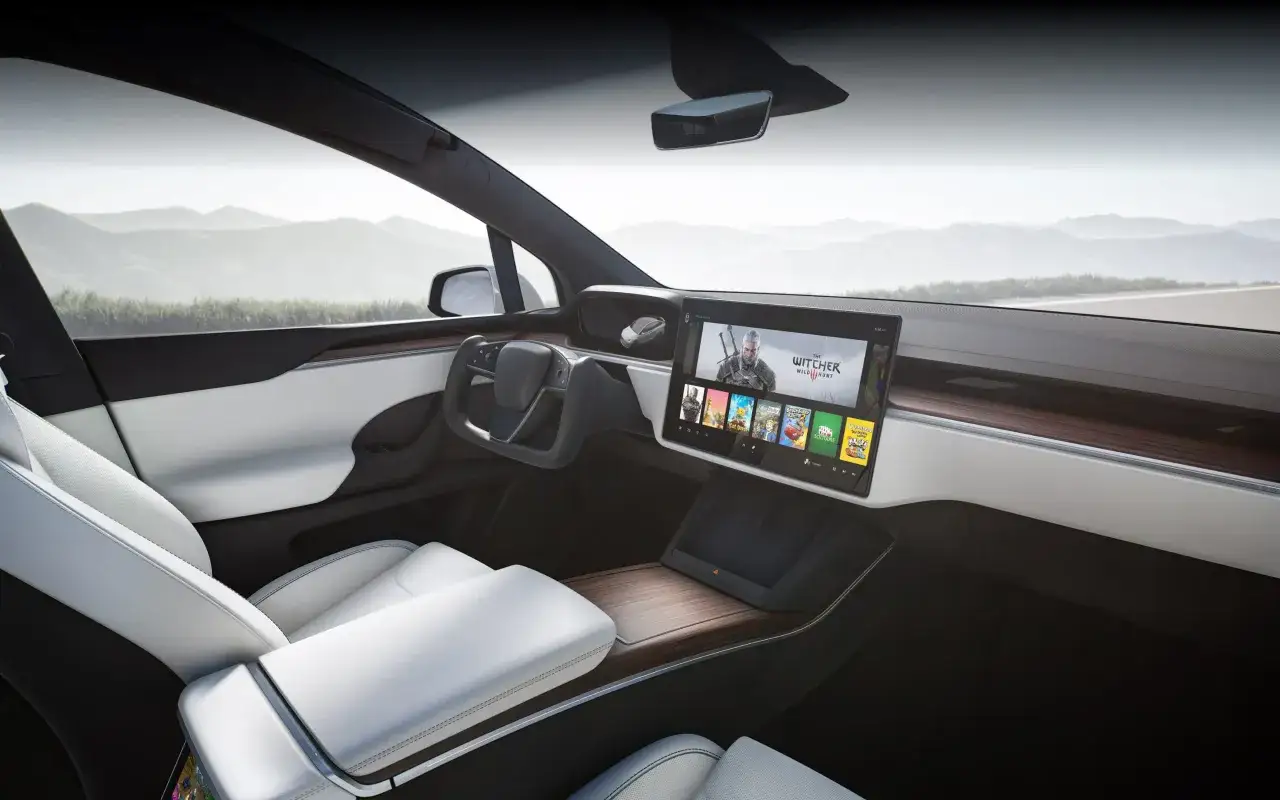 Wnętrze Tesli X z ekranem pokazującym gry, idealne na długie podróże. Sprawdź tesla x cena i możliwości tego auta.