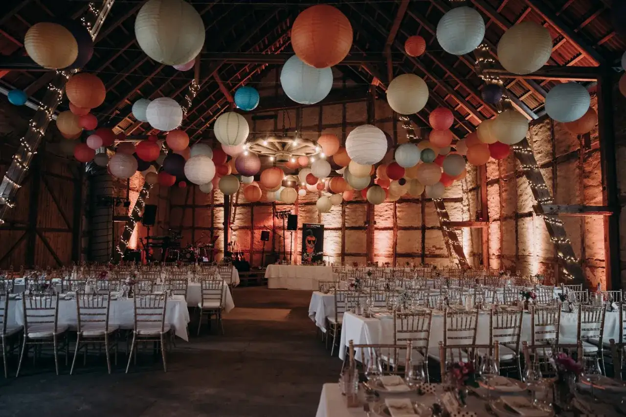 Festlich geschmückte Scheune für eine Hochzeit, mit bunten Lampions und Lichterketten.