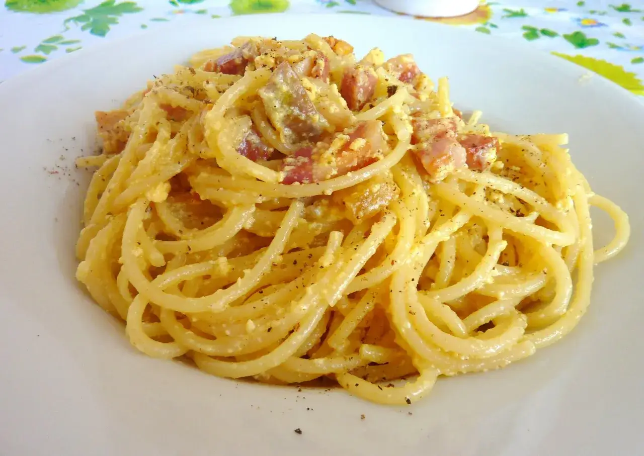 Un piatto invitante di spaghetti alla carbonara, con guanciale croccante e una cremosa salsa all'uovo e pecorino, spolverato di pepe nero.