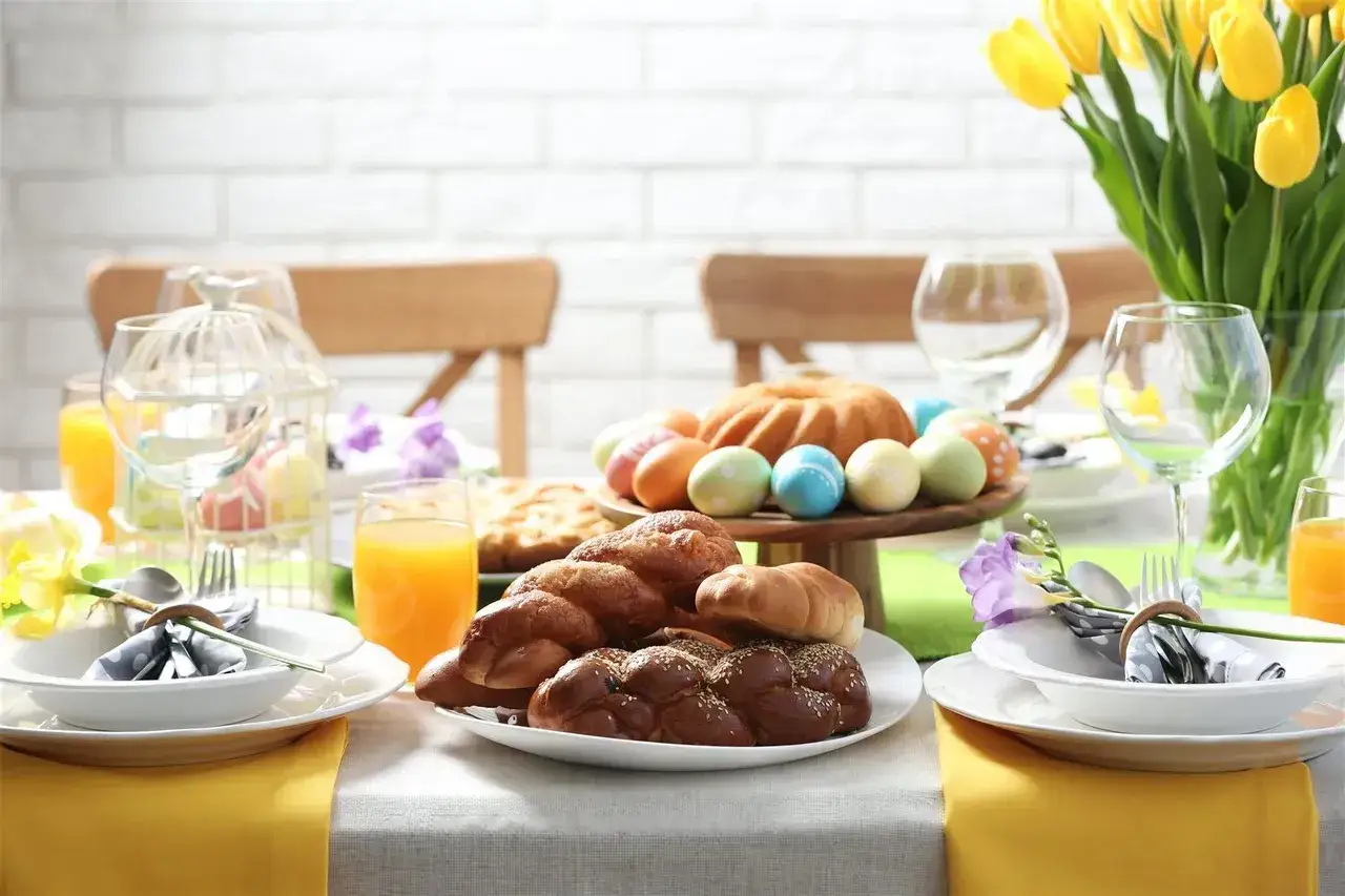 Nowoczesne potrawy wielkanocne: babka, baranek, kolorowe jajka, pieczywo i tulipany na stole.