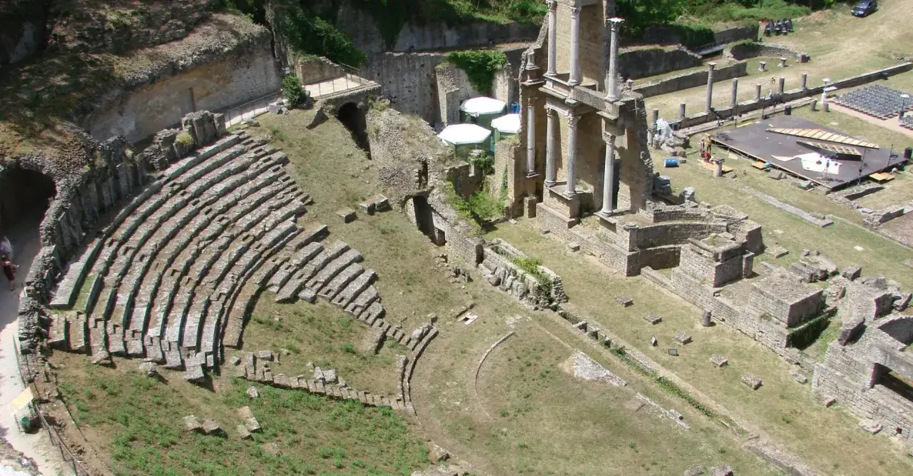Antico teatro romano di Volterra, con gradinate in pietra e resti di edifici antichi.