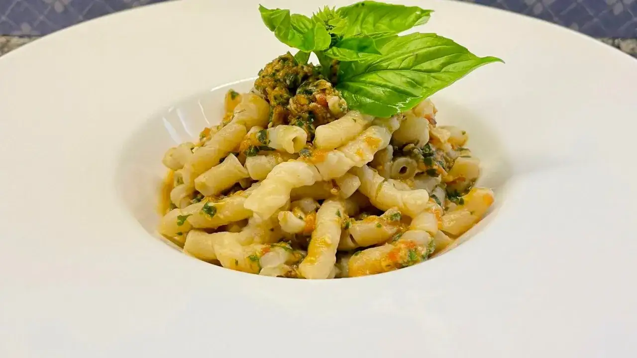 Busiate alla trapanese, pasta fresca con pesto di mandorle, pomodoro e basilico, un piatto siciliano gustoso.