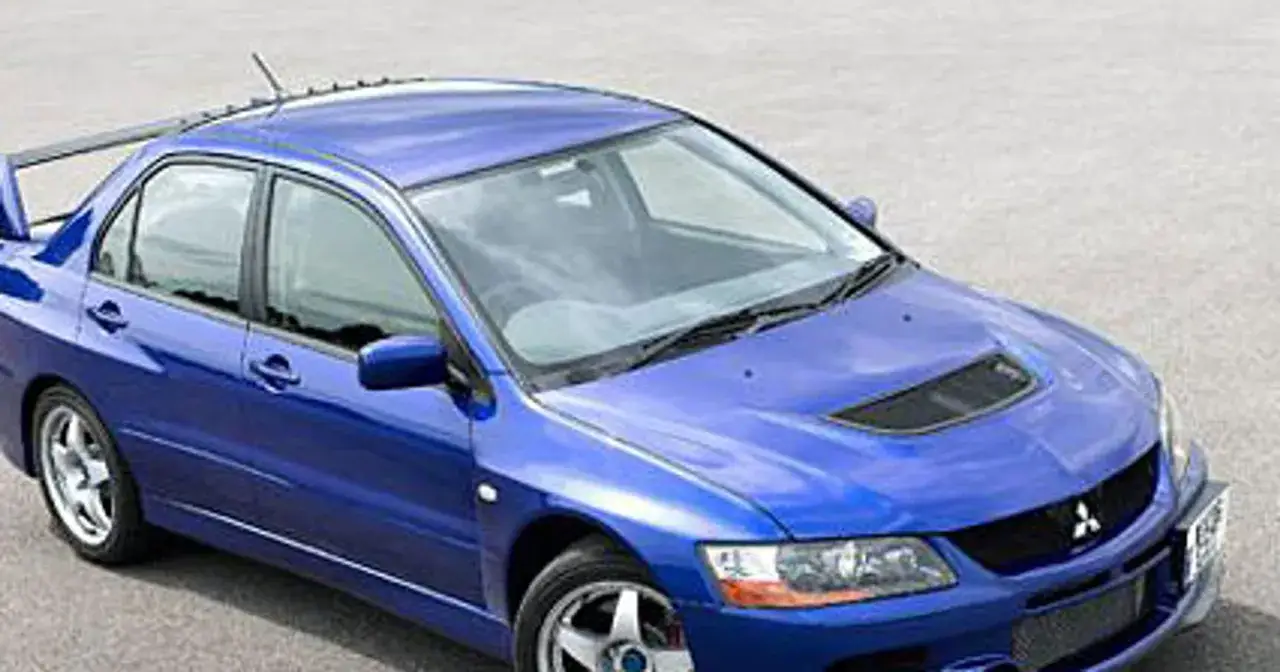 Niebieski Mitsubishi Lancer Evo 9 z charakterystycznym wlotem powietrza na masce i dużym spojlerem, gotowy do akcji.