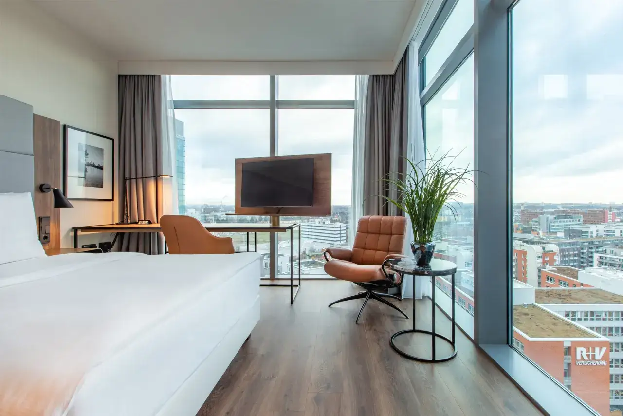 Pokój w hotelu **Frankfurt Radisson Blu** z widokiem na miasto, łóżkiem, fotelem i biurkiem.