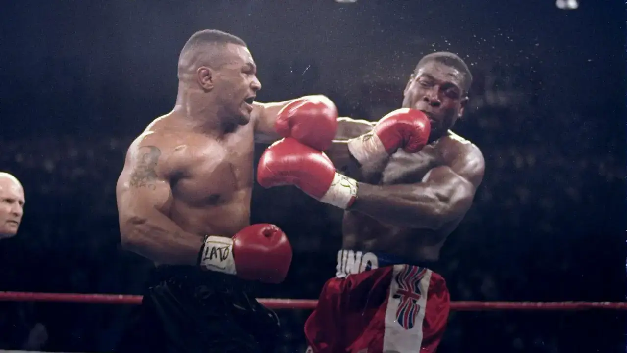 Mike Tyson in his 20s lands a powerful punch during a boxing match.