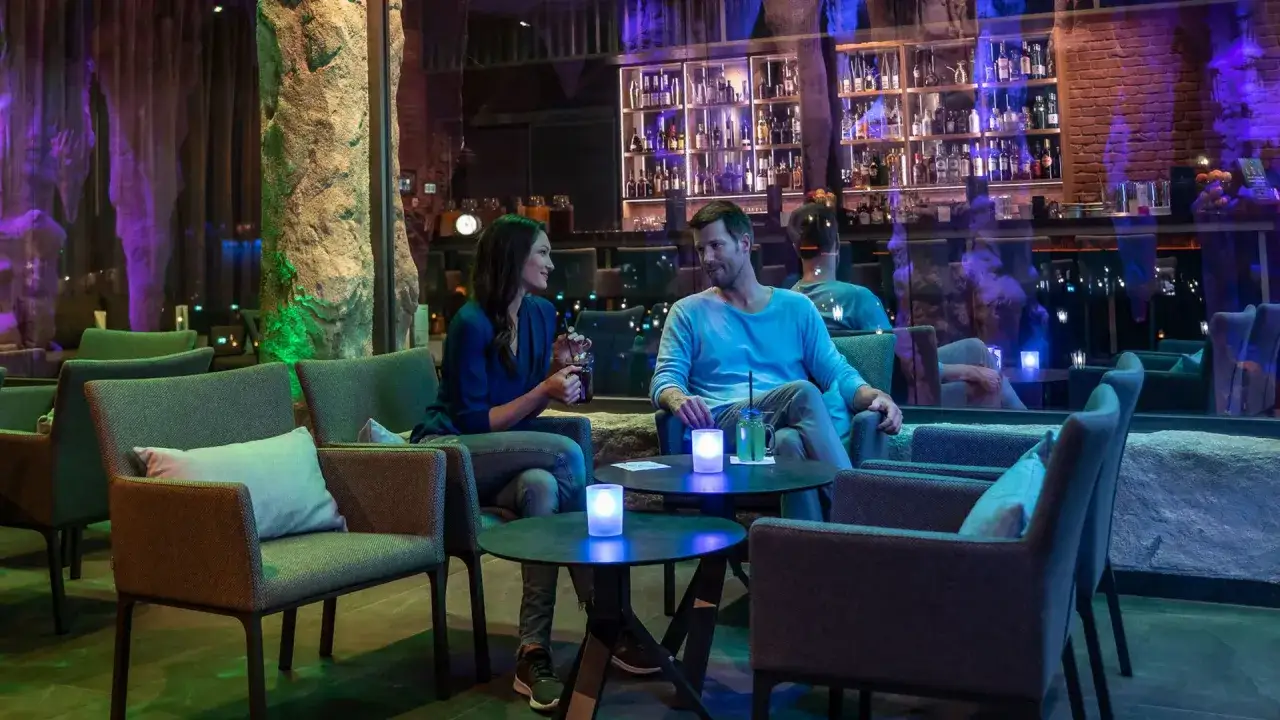Ein Paar genießt Getränke in einer stilvollen Bar mit Felsformationen und gedämpftem Licht. Ein perfekter Ort für ein romantisches rulantica essen.
