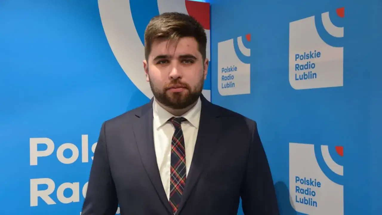Młody mężczyzna w garniturze przed logo Polskiego Radia Lublin. Działaczy zaskoczyła kandydatura Jakuba Banaszka na premiera.
