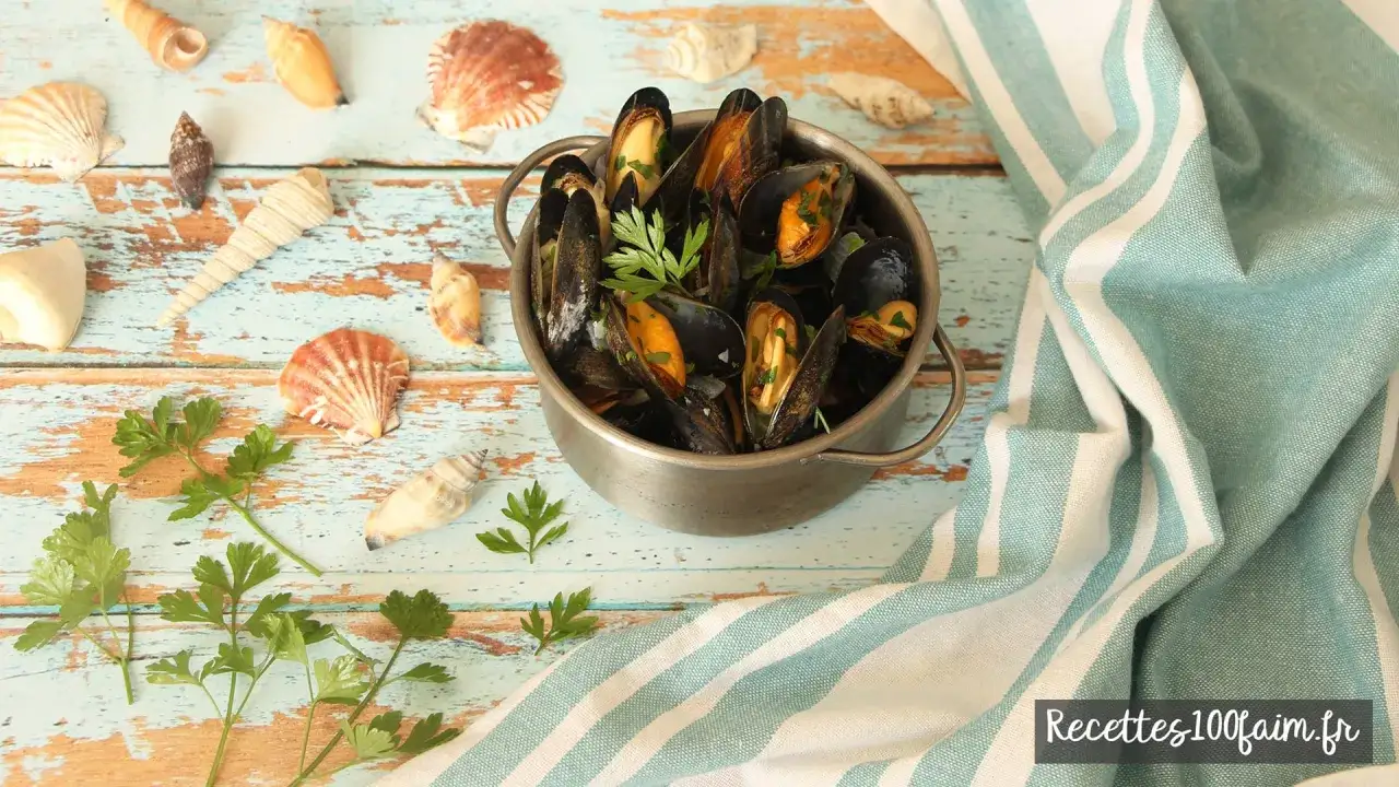 Un plat de moules marinières fumantes, garni de persil frais, entouré de coquillages sur une table en bois patiné.