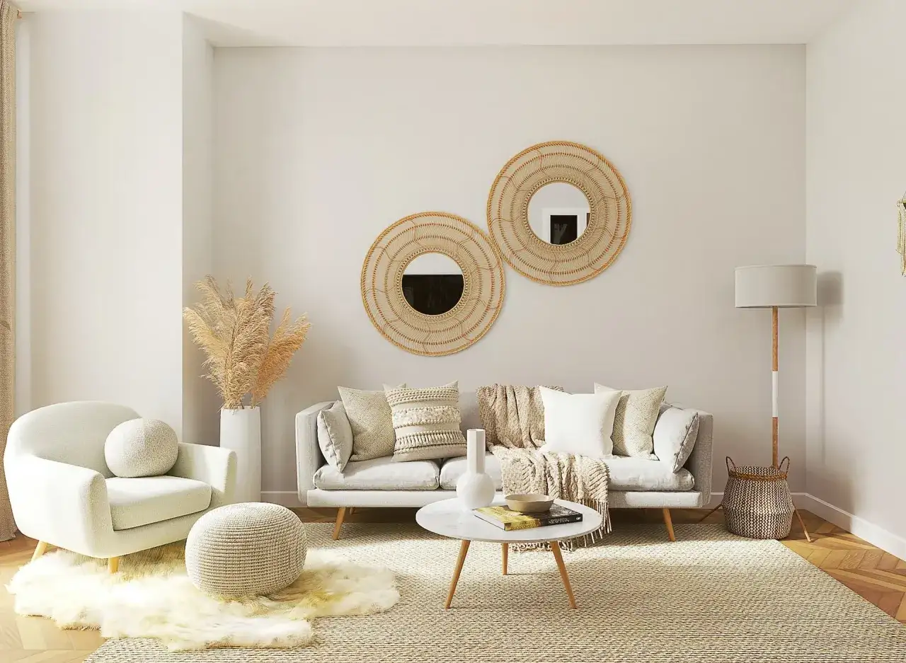 Salotto con divano grigio, poltrona bianca, tavolino rotondo in marmo e specchi decorativi in rattan. Un'oasi di **arredamento contemporaneo chic**.