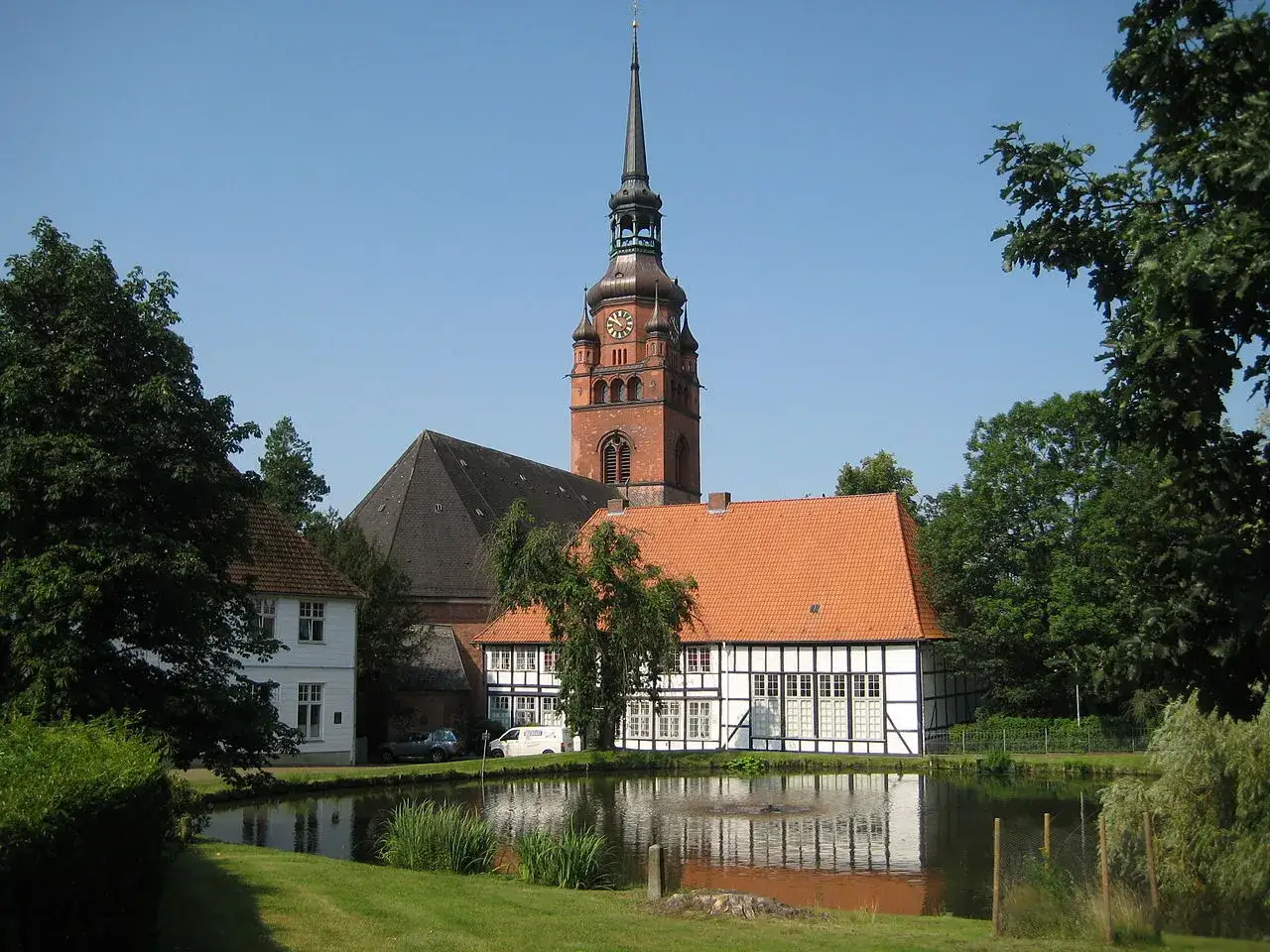 Kirchturm und Fachwerkhäuser in der itzehoe altstadt spiegeln sich in einem Teich.