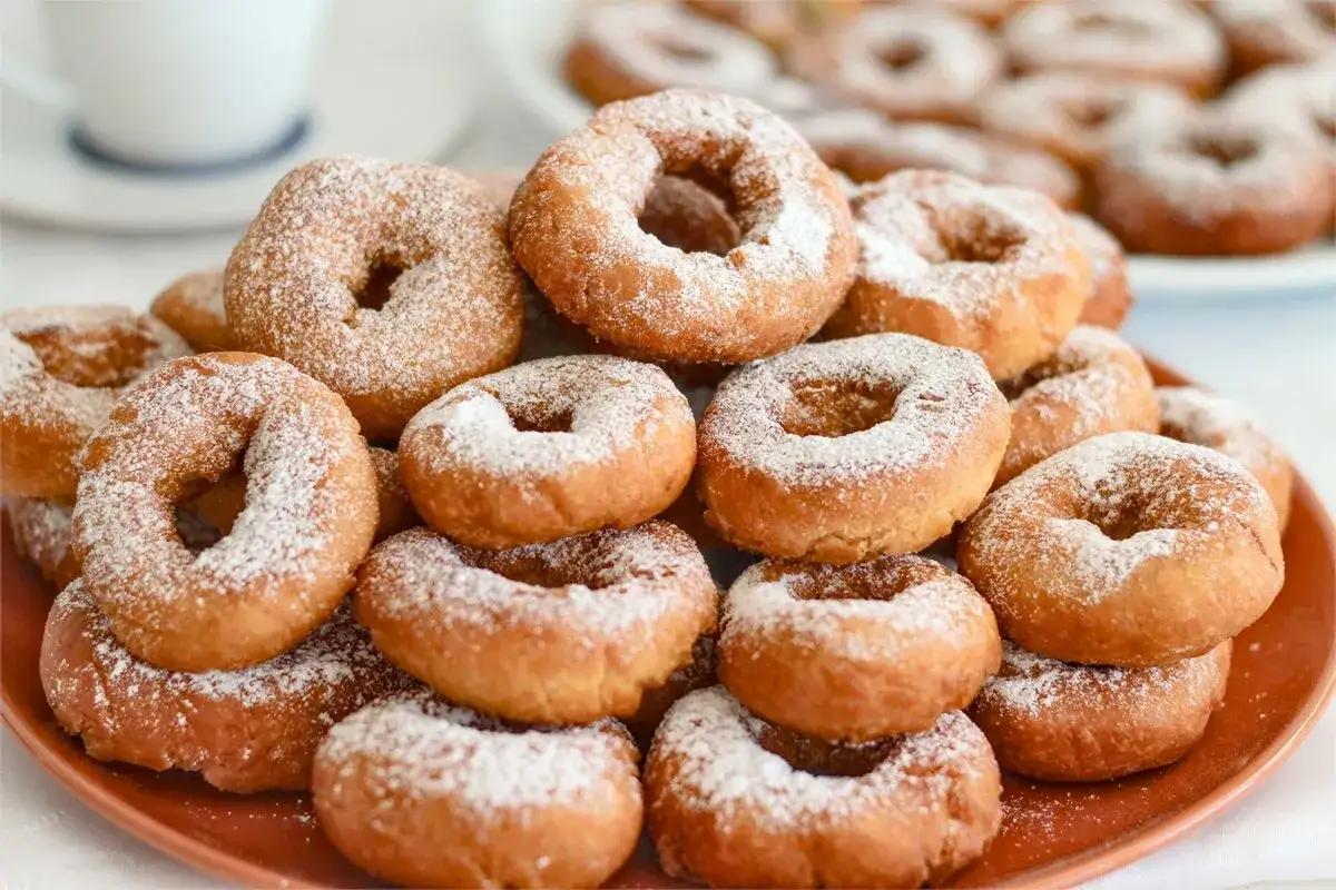 Montón de rosquillas caseras esponjosas espolvoreadas con azúcar glas, listas para disfrutar.