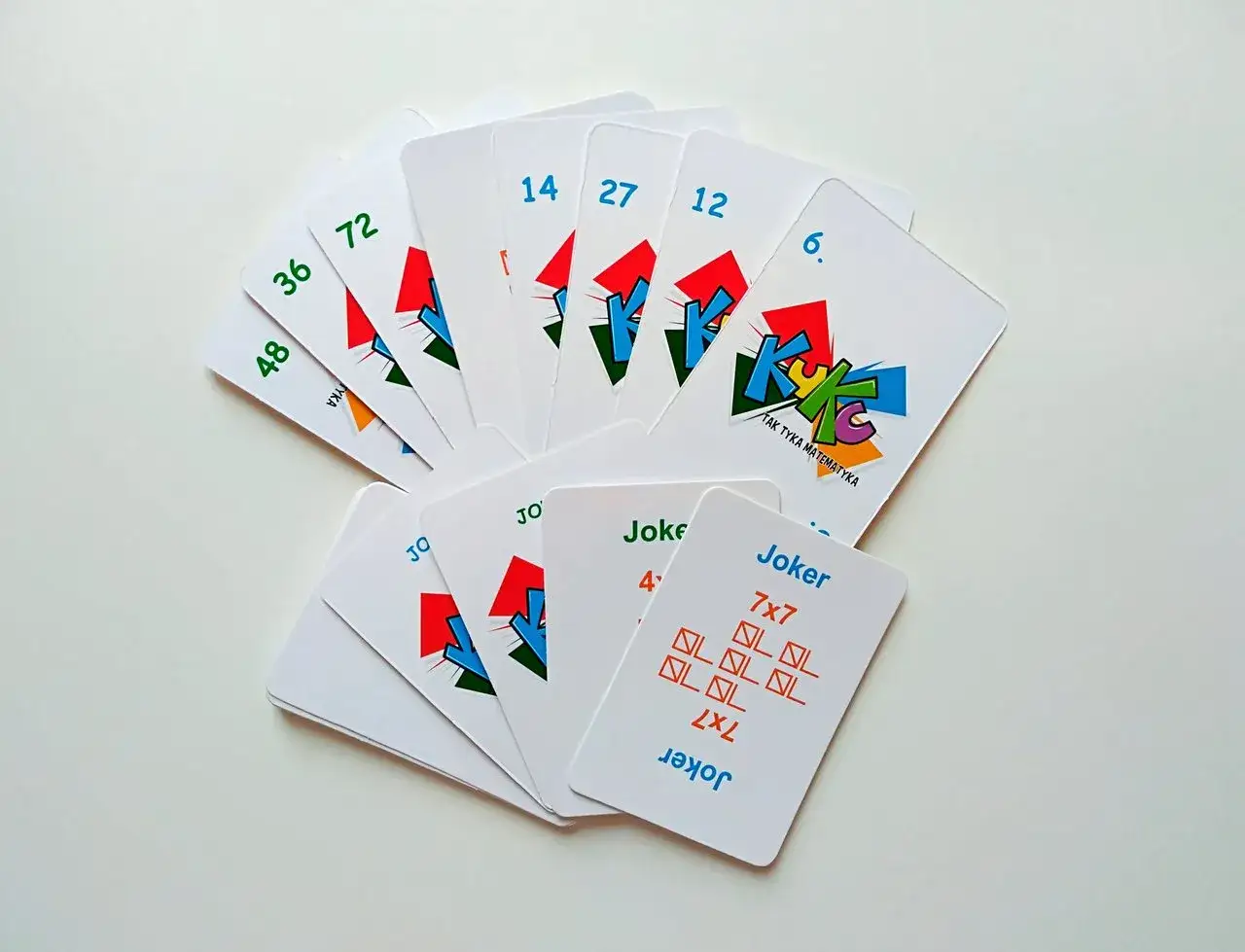 Karty do gry w kuku, z cyframi i symbolami matematycznymi. Na jednej z kart Joker widnieje mnożenie 7x7.