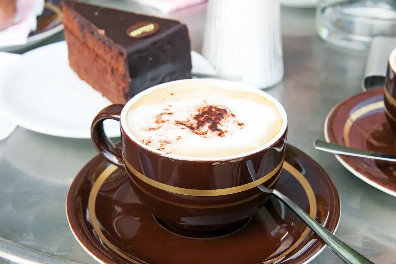 Eine Melange, ein klassisches Wiener Kaffeegetränk, wird hier mit einem Stück Sachertorte serviert.