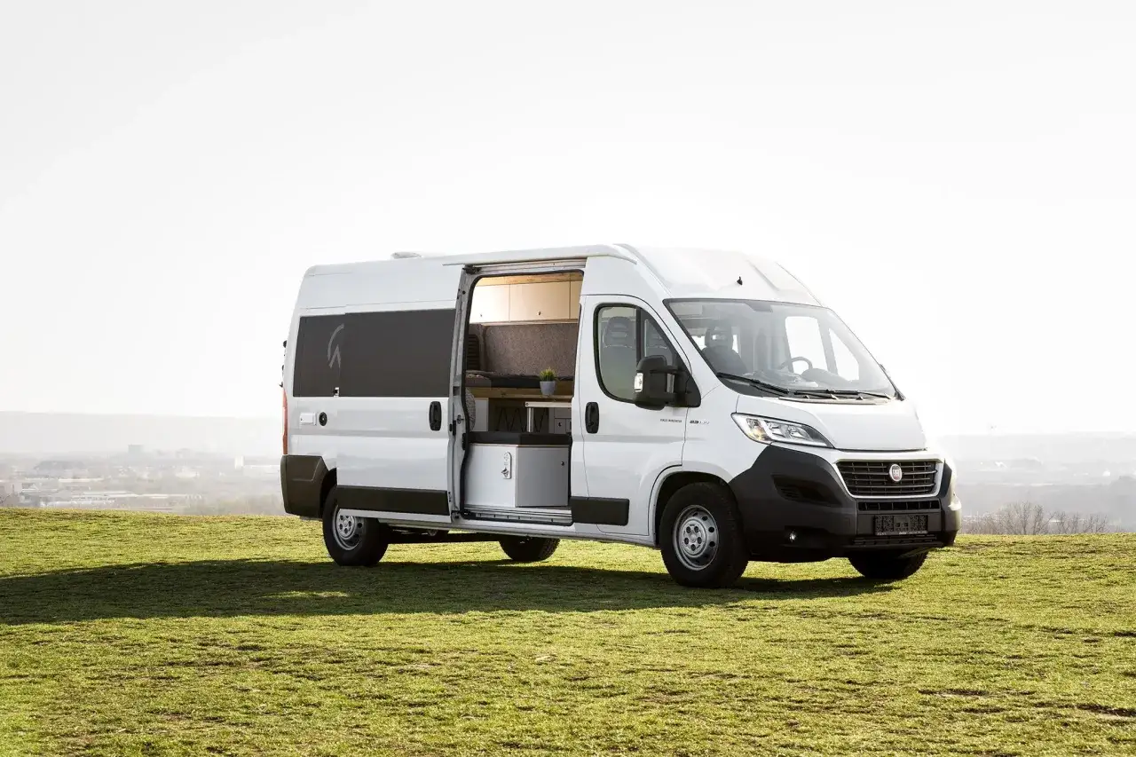 Vit Fiat Ducato husbil med &ouml;ppen skjutd&ouml;rr som visar inredning. Perfekt f&ouml;r &auml;ventyr, en av m&aring;nga fiat ducato modeller.
