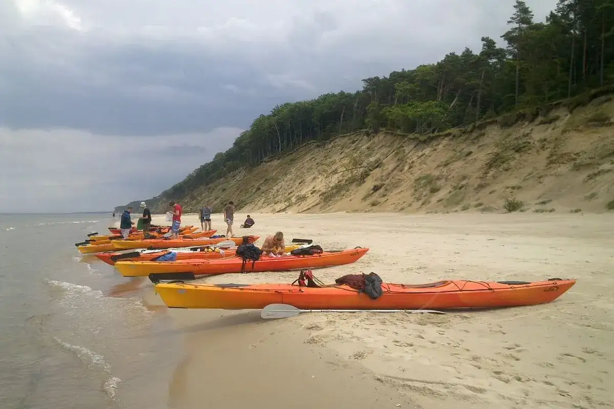 Pomarańczowe kajaki czekają na plaży na przygodę. Wspaniałe atrakcje nad morzem dla aktywnych.