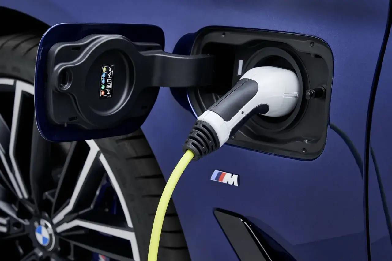 Ładowanie hybrydowego BMW 530e. Wtyczka podłączona do portu ładowania, obok widoczny znaczek M.