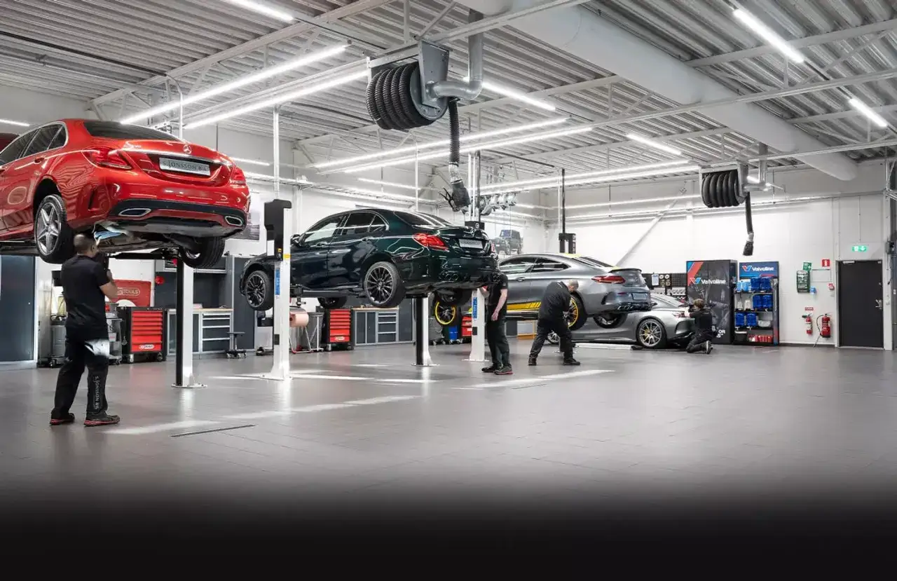 Mekanisker utför service på Mercedes-bilar i en modern verkstad.