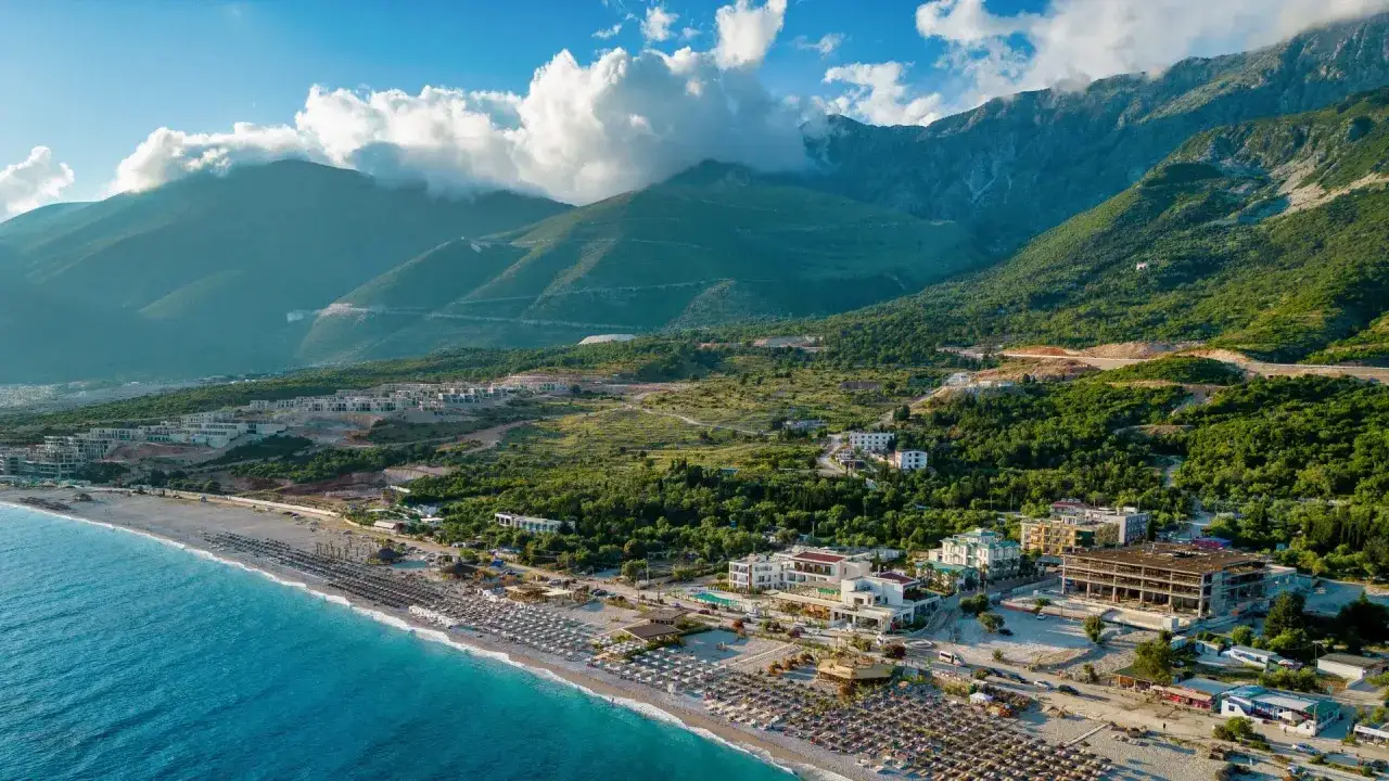 Malownicze albania plaże z turkusową wodą, górami w tle i hotelami. Idealne miejsce na wakacje.