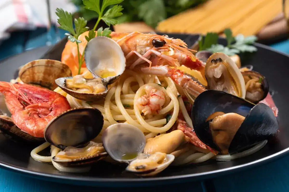 Un piatto invitante di spaghetti allo scoglio, ricco di gamberi, cozze e vongole, guarnito con prezzemolo fresco.