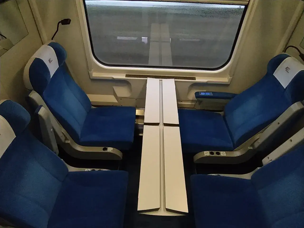 Komfortowe fotele i stolik w przedziale. Takie udogodnienia daje 1 klasa w Intercity, zapewniając wygodną podróż.