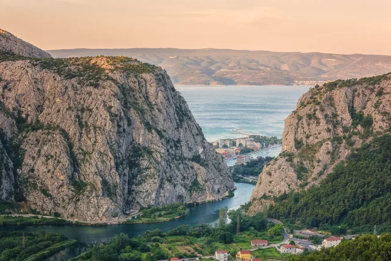 Vue spectaculaire d'une gorge rocheuse en Croatie, parfaite pour une randonnée. La rivière serpente vers la mer Adriatique, bordée de villages pittoresques.