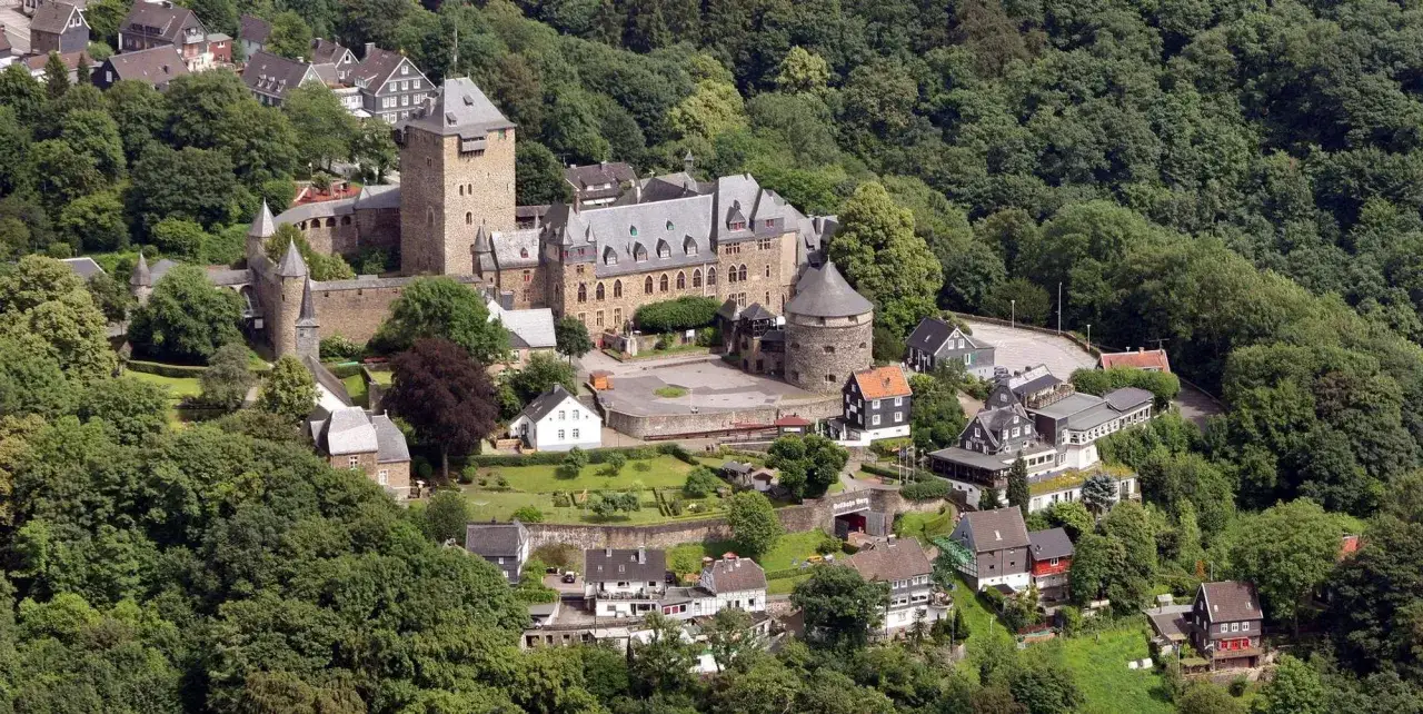 Das Schloss Burg an der Wupper thront majest&auml;tisch auf einem H&uuml;gel, umgeben von &uuml;ppigem Gr&uuml;n.