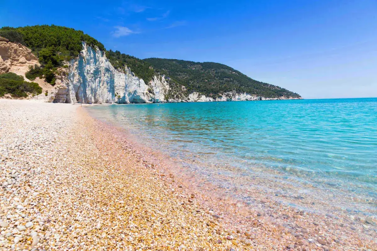 Spiaggia di ciottoli con scogliere bianche e mare cristallino. La cala rosa offre un paesaggio mozzafiato.
